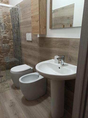 a bathroom with a sink and a toilet and a mirror at Piazza San Giorgio in Dolianova
