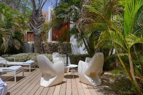 a patio with white chairs and tables and palm trees at Yam Suf by Isrotel Collection in Eilat