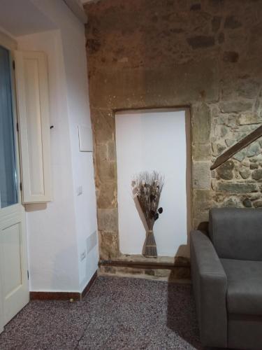 a room with a white wall with a vase of flowers at Piazza San Giorgio in Dolianova