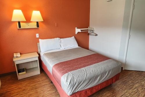 a small bedroom with a bed with an orange wall at Motel 6-Coeur D'Alene, ID in Coeur d'Alene