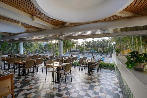 a restaurant with tables and chairs and a pool at Yam Suf by Isrotel Collection in Eilat