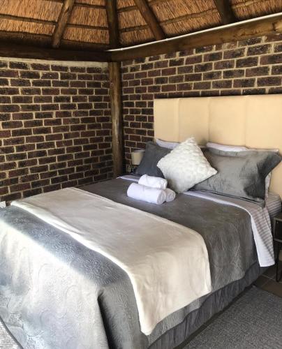 a bedroom with a large bed in a brick wall at Pomona Lodge in Kempton Park