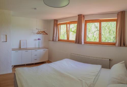 a bedroom with a white bed and two windows at Ferienwohnung Hehl in Burgberg