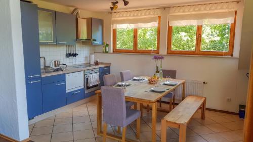 cocina con mesa de madera y armarios azules en Ferienwohnung Hehl, en Burgberg