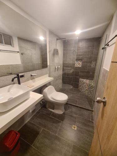 y baño con aseo, lavabo y ducha. en Hotel Suramericana, en Medellín