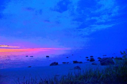 a sunset over the ocean with rocks in the water at Pilava in Roja