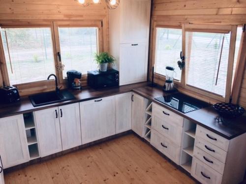 una cucina con armadi bianchi e finestre in una cabina di Domek nad jeziorem 