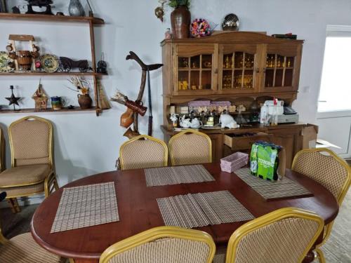 a dining room table with chairs and a wooden cabinet at Cabana Dor de-Acas / Restaurant Dor de-Acas in Gura Haitii