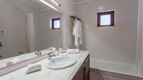 ein Badezimmer mit einem Waschbecken, einem Spiegel und einer Badewanne in der Unterkunft Cozy Algarve Home with Vineyard View Near Beaches in Porches