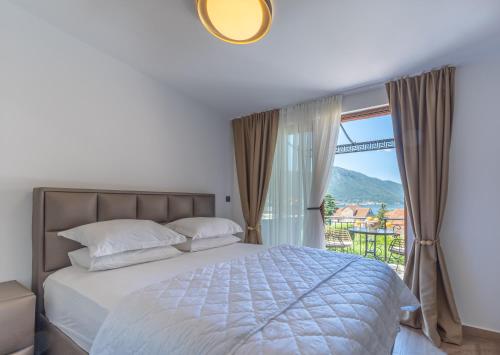 a bedroom with a bed and a balcony with a view at Apartments Nikčević in Kotor