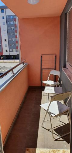 - deux chaises et des tables sur un balcon avec un mur orange dans l'établissement AVA Apartment Istočno Sarajevo, à Lukavica