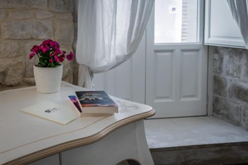 a book and flowers on a table next to a door at Scicli Albergo Diffuso in Scicli