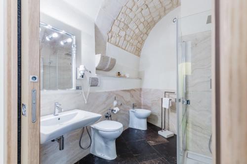a bathroom with a sink and a toilet and a mirror at Scicli Albergo Diffuso in Scicli