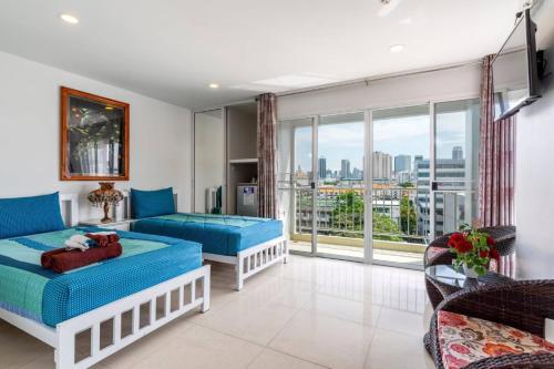 a living room with two beds and a large window at Parvena Hotel Sathorn in Bangkok