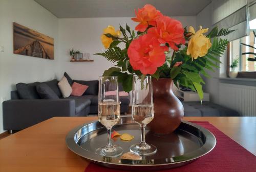 two wine glasses and a vase with flowers on a table at Appartement - FeWo Wenne in Langenau