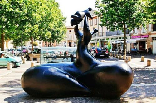 a bronze statue of a woman holding a cat at T5 L'ATELIER in Valence-dʼAgen