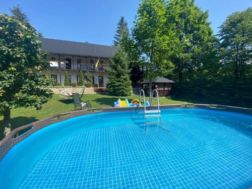 - une piscine dans une cour avec une maison dans l'établissement Zorianyy Guest House, à Mykulychyn