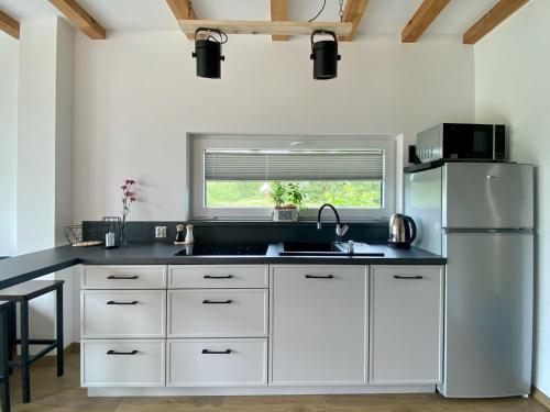 a kitchen with white cabinets and a refrigerator at Chachatki Kopalino in Kopalino