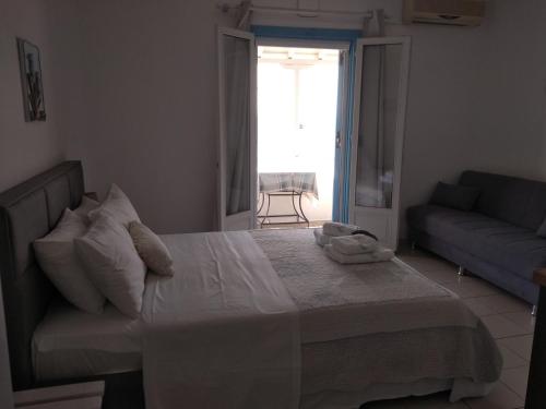 a bedroom with a bed with a couch and a window at Anastasia Studios & Apartments in Panormos Skopelos