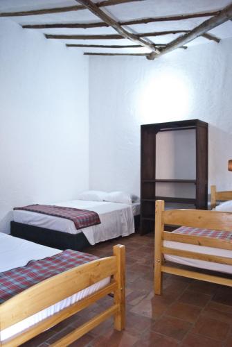 a room with two beds and two benches in it at Casa Aparicio Lopez in Barichara