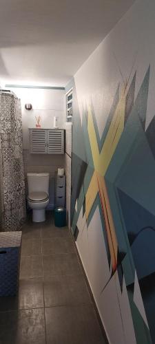 a bathroom with a toilet and a painting on the wall at Label kafé in Bouillante