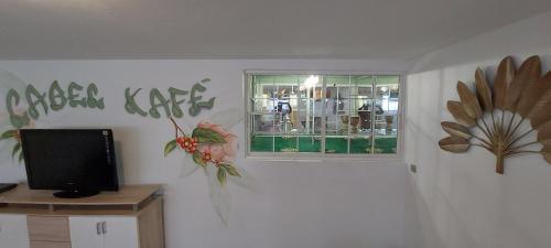 a living room with a window and a television at Label kafé in Bouillante