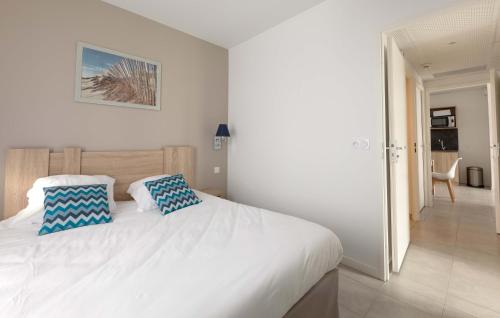 a bedroom with a white bed with two blue pillows at Résidence Prestige Odalys Rêve d'île in Rivedoux-Plage