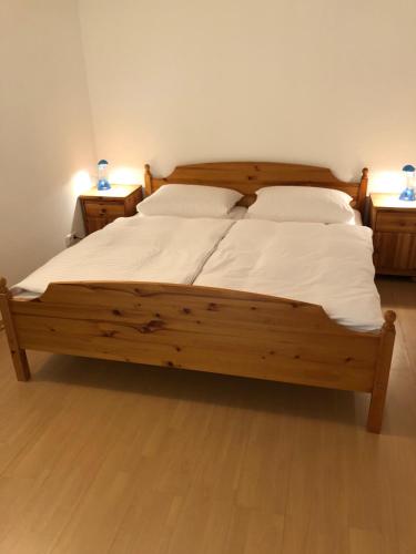 ein großes Holzbett mit weißer Bettwäsche und Kissen in der Unterkunft Ferienwohnung Wasserfall in Schliersee