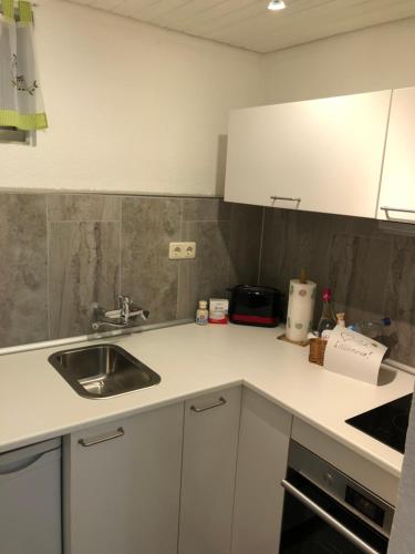 a kitchen with white cabinets and a sink at Ferienwohnung Wasserfall in Schliersee