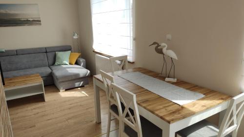 a living room with a table and a bird statue on a dining table at Apartament Słoneczny Węgorzewo 74m2 in Węgorzewo
