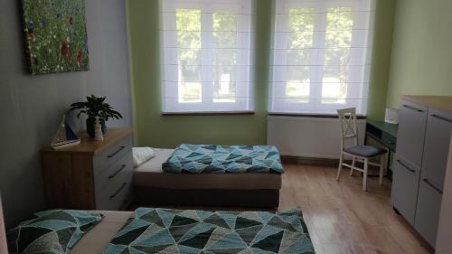 een slaapkamer met 2 bedden, een bureau en een stoel bij Apartament Słoneczny Węgorzewo 74m2 in Węgorzewo