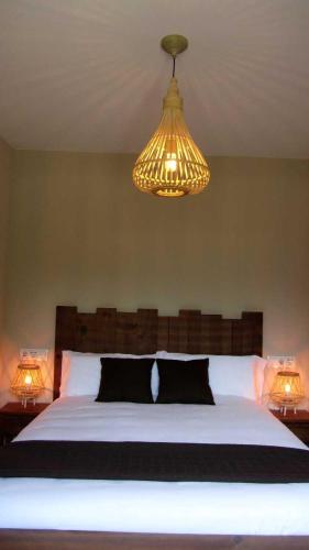 a bedroom with a large bed and a chandelier at La Pintada Casa Rural in Cañícosa