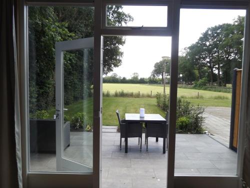 une porte coulissante en verre menant à une terrasse avec une table. dans l'établissement Het Broekeroord, à Wezep