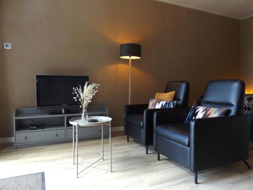 a living room with two black chairs and a tv at Het Broekeroord in Wezep