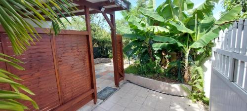 a wooden fence with a gate and a garden at Label kafé in Bouillante