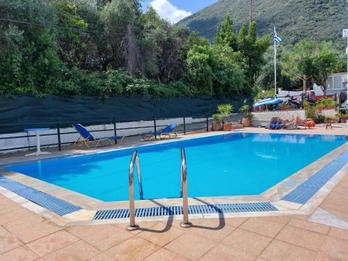a blue swimming pool with two chairs and a mountain at ZOI & ALEXIA APARTMENTS in Ipsos