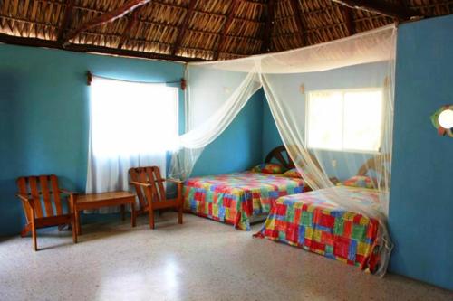 a bedroom with two beds and a table and chairs at Hotel Cafe del Sol in Monterrico