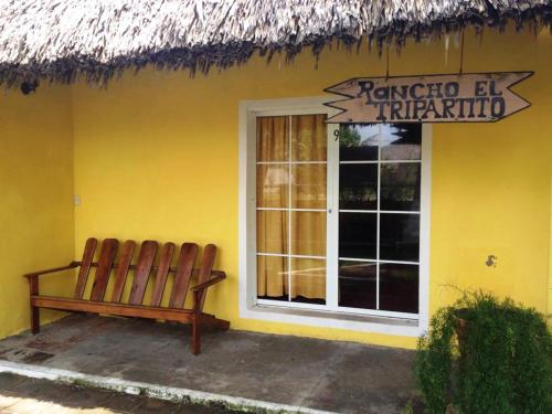 a bench sitting outside of a yellow building at Hotel Cafe del Sol in Monterrico
