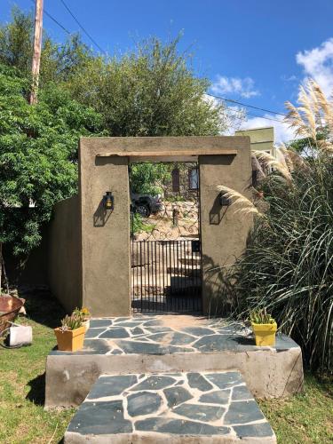 a gate to a garden with a stone walkway at La Osadia Cabañas y Suites Solo Adultos in Mina Clavero