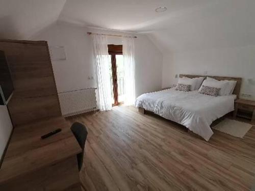 a white bedroom with a bed and a dresser and a window at Farma & Apartmani OPG Sasa Delic in Korenica