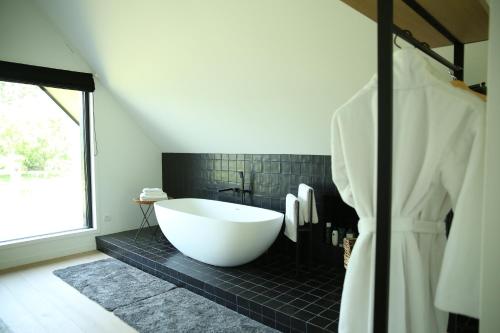 ein Badezimmer mit einer großen Badewanne und schwarzen Fliesen in der Unterkunft Rozeboom Loft in Aartrijke