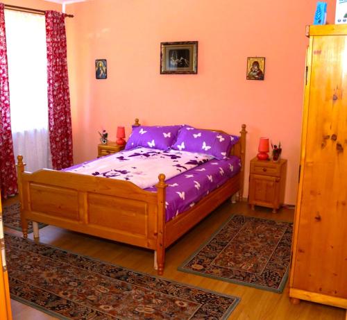 - une chambre dotée d'un lit avec des draps violets dans l'établissement Apartament Iulia, à Geoagiu Băi