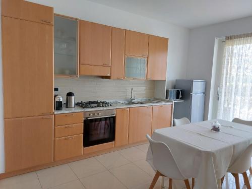 cocina con armarios de madera y mesa con mantel blanco en CasaRò, en Albano SantʼAlessandro