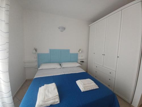 um quarto com uma cama azul com duas toalhas em Il Suono delle Conchiglie - Lido Conchiglie Gallipoli em Gallipoli