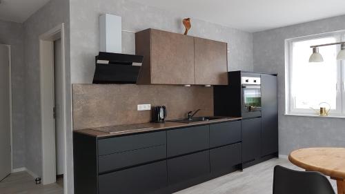 a kitchen with black cabinets and a sink and a table at Ferienwohnung Chattengau in Niedenstein