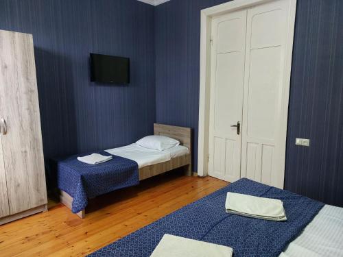 a bedroom with two beds and a tv on the wall at Lakeside Green Balcony Home in Tskaltubo
