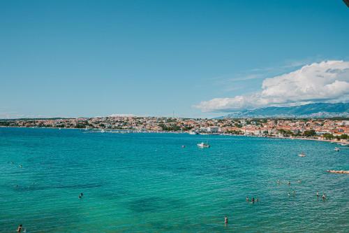 a group of people in the water at a beach at Kaneo beach hotel Novalja in Novalja