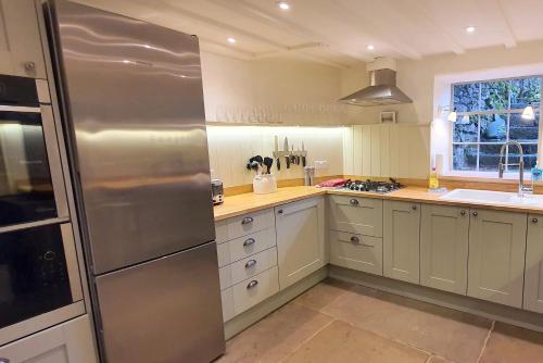 a kitchen with a stainless steel refrigerator and white cabinets at Candle House, Winster, in the Peak District in Winster