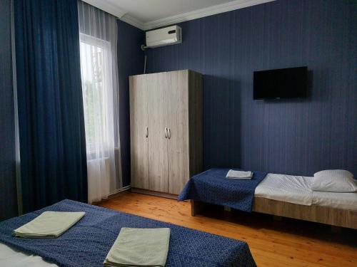 a room with two beds and a cabinet and a television at Lakeside Green Balcony Home in Tskaltubo