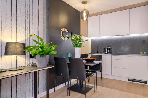 a kitchen with white cabinets and a table and chairs at InPoint Apartments G15 near Old Town & Kazimierz District & Optional Paid Parking in Kraków